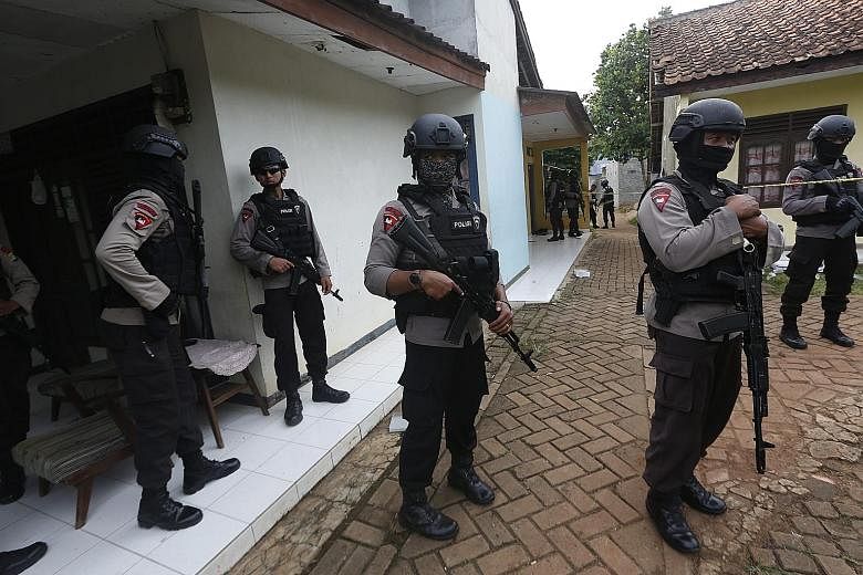 Indonesian anti-terror officers standing guard during a raid on Wednesday in South Tangerang. Police said three terrorists were shot dead and a fourth arrested, and six packets, each containing about two bombs, were seized from a house in the area.