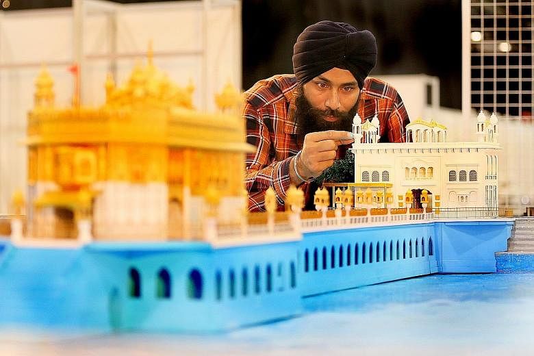 Above: Artist Gurpreet Singh, who is from India, putting the final touches to a paper model of the Golden Temple in Amritsar. Left: Volunteers getting ready for the four-day Sikh festival at the Singapore Expo, which opens today.