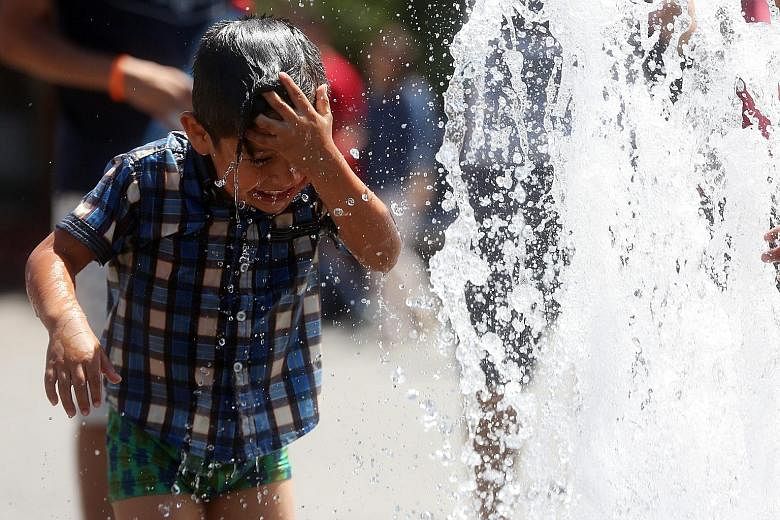 A boy cooling down at a water feature on a hot day at Buin Zoo, 30km south of Santiago, Chile, earlier this month. Wildfires raging through Alberta, Canada, earlier this year. Greenhouse gases that trap heat cause temperatures to rise, leading to ext