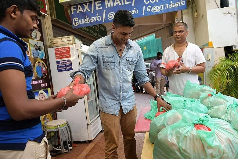 A migrant worker receiving food on Christmas Day in Little India from Mr Muthusamy (centre) and Mr Bala. Mr Bala aims to raise enough money to cook and give away 10,000 packets to the needy by Chinese New Year. He has raised enough for 450 packets, 1