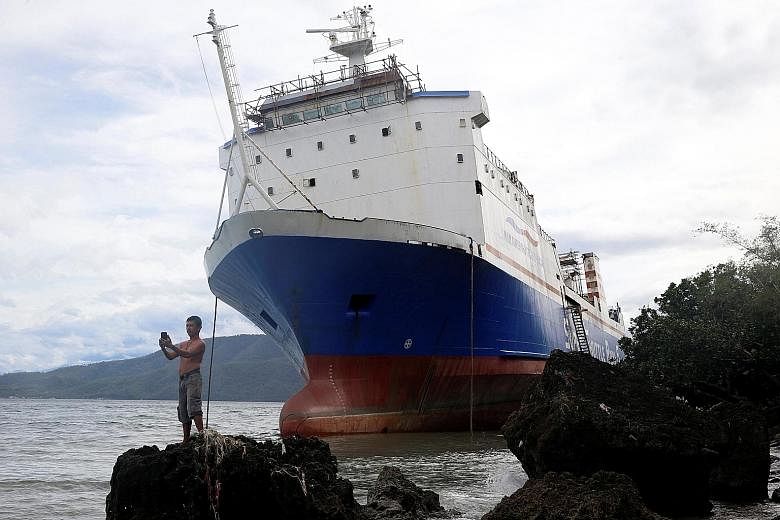 A resident taking a selfie in front of an inter-island ferry that was swept ashore at the height of Typhoon Nock-Ten in Mabini, Batangas, in the Philippines, on Monday. The storm took out power in many eastern provinces and flooded roads and farms. I