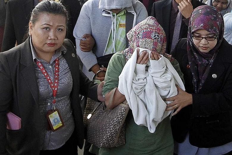 The accused (from front) Fauziah, Awang and Lim hiding their faces while being taken to court in Kota Kinabalu yesterday.