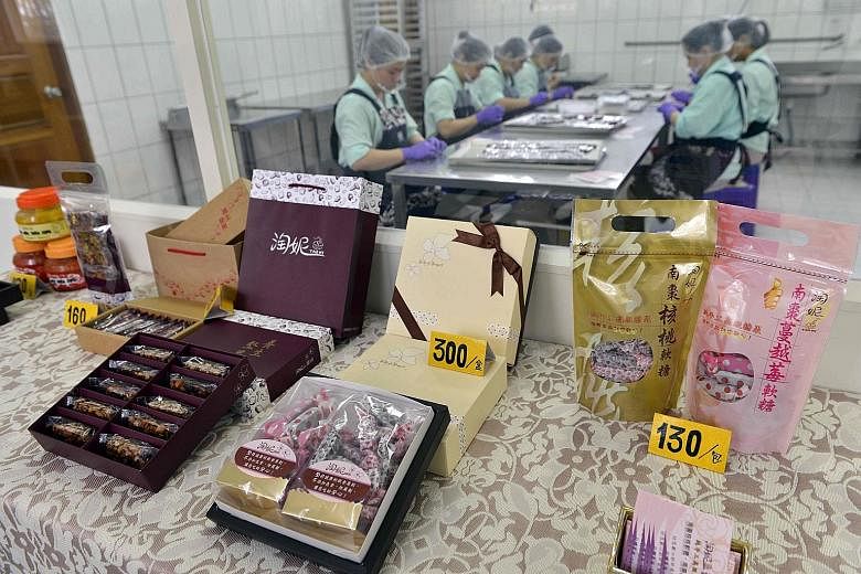 Food items made by prisoners on display as inmates work in the background at a correctional facility in Taoyuan, northern Taiwan. The additive-free delicacies made by prison inmates have gained a loyal public following, and generate hundreds of milli