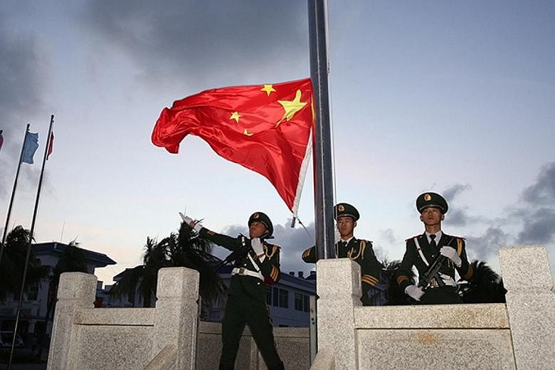 Soldiers conducting a flag-raising ceremony at Chinese-occupied Woody Island in the Paracels yesterday morning. Similar ceremonies were conducted at other disputed islands in the Paracels and the Mischief Reef in the Spratlys. China's assertive claim