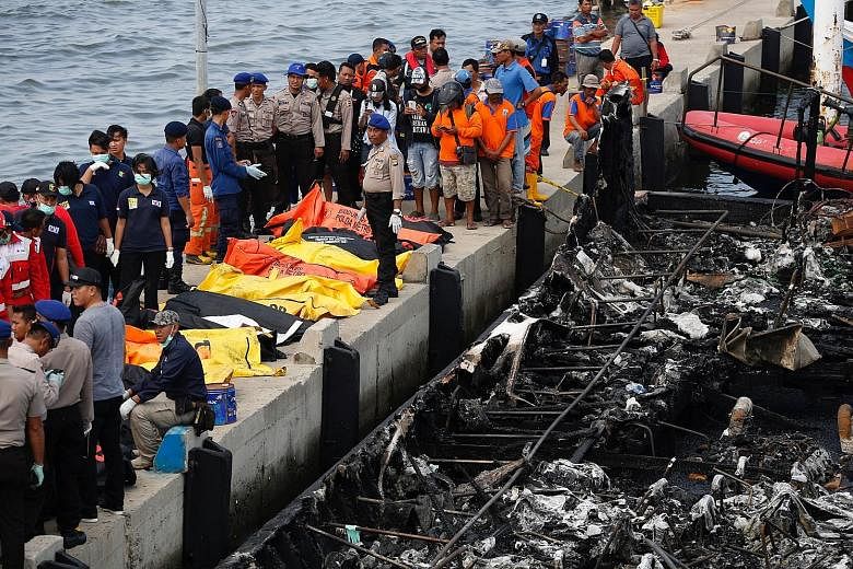Police officers and rescue workers preparing to remove body bags at Muara Angke port in Jakarta yesterday. A boat carrying hundreds of local tourists caught fire shortly after it left port to head to the popular holiday island of Tidung, the national