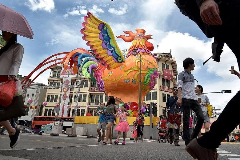 Pedestrians walk past the imposing centrepiece of this year's Chinatown light-up, a 13m-tall rooster with outspread wings at the junction of Eu Tong Sen Street, New Bridge Road and Upper Cross Street. Four thousand handcrafted lanterns, including thi