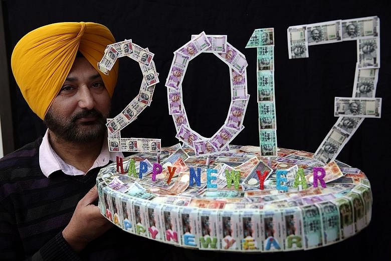 Indian artist Harwinder Singh Gill showing his New Year artwork made with pictures of Indian currency notes. Mr Modi has defended his recent decision to abolish high-denomination banknotes.