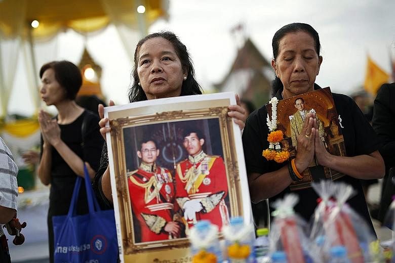 Thais offering New Year prayers with portraits of Thai King Maha Vajiralongkorn and his father, the late King Bhumibol, during the mass alms-giving religious ceremony at the Bangkok Metropolitan Administration City Hall yesterday.