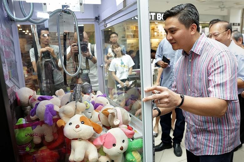Bishan-Toa Payoh GRC MP Saktiandi Supaat trying out the claw machine yesterday. Money raised from users trying their luck at getting a stuffed toy from the machine will go towards THK's services.