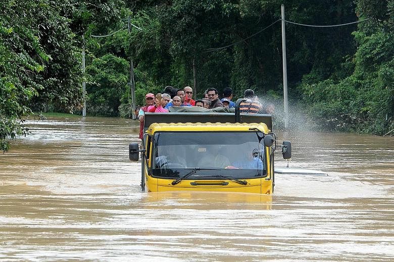 Flood victims using a lorry to travel in Kampung Bekuk in the north-eastern Malaysian state of Terengganu after a road was closed to light vehicles yesterday. The number of evacuees rose sharply to 12,910 from 4,352 the previous day after heavy rain 
