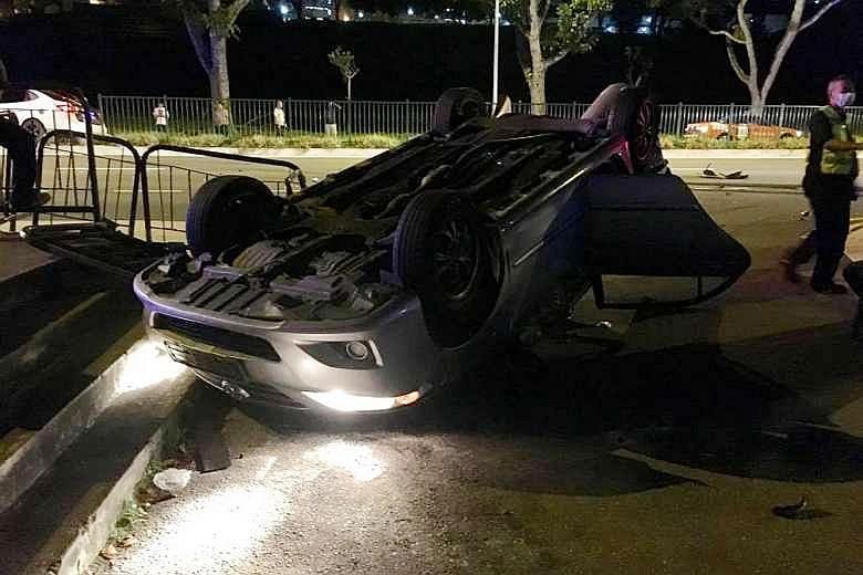 The overturned silver sedan after a two-car collision early yesterday. The other vehicle was a white sedan which mounted the road's central divider. The four people who were injured were taken to hospital.