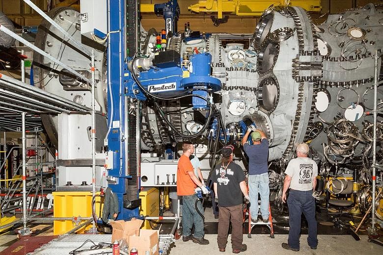 Workers use a robotic arm to install components of a gas turbine at GE's factory in Greenville, South Carolina. The recovering manufacturing sector is expected to give a shot in the arm to the world economy this year, but growth is still likely to be