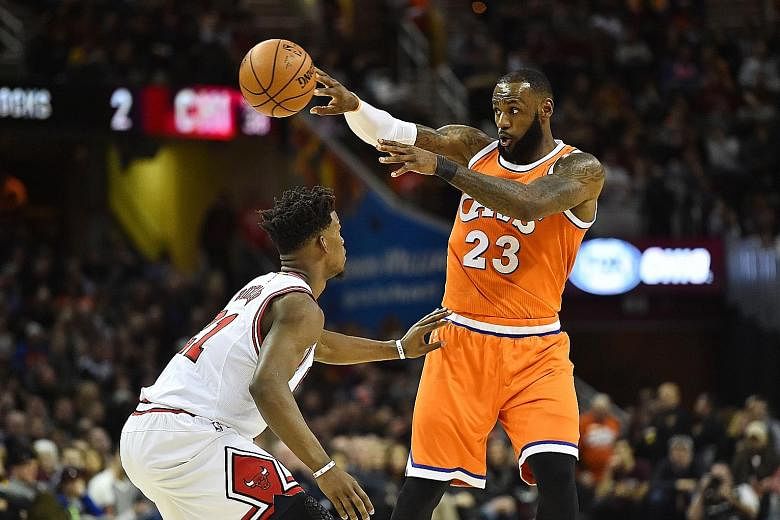 Cavaliers forward LeBron James passes as Bulls forward Jimmy Butler defends during the first half of their NBA clash at Quicken Loans Arena. James (31 points) and Butler (20) were their respective teams' top scorers.