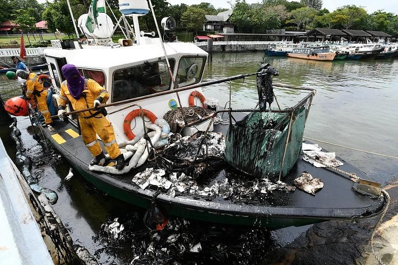Oil floating on water near mangroves at Pulau Ubin yesterday. Cleanup operations were carried out on a 100m stretch of Noordin beach. A mother with her two children picking up seashells yesterday on Changi beach, which was lined with bags filled with
