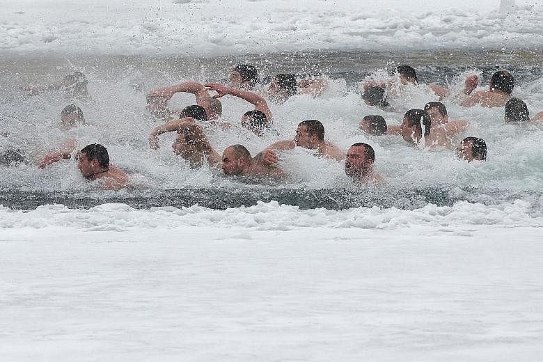 Swimmers racing in the icy waters of a lake in Sofia, Bulgaria, to find a cross during Epiphany Day celebrations yesterday. Traditionally, an Eastern Orthodox priest throws a cross into the water, and it is believed that the one who retrieves it will