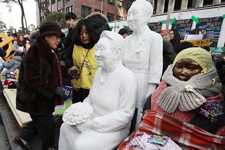 Former comfort woman Kim Bok Dong (left) next to a statue of her during a rally in front of Japan's Embassy in Seoul on Wednesday. Another statue commemorating women forced to work in Japanese military brothels during World War II, which went up in B
