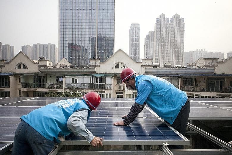 Workers installing solar panels on a rooftop in Wuhan, China, last month. This week, China's National Energy Administration announced that it will plough 2.5 trillion yuan (S$518 billion) into renewable power generation by 2020, as it moves from trad