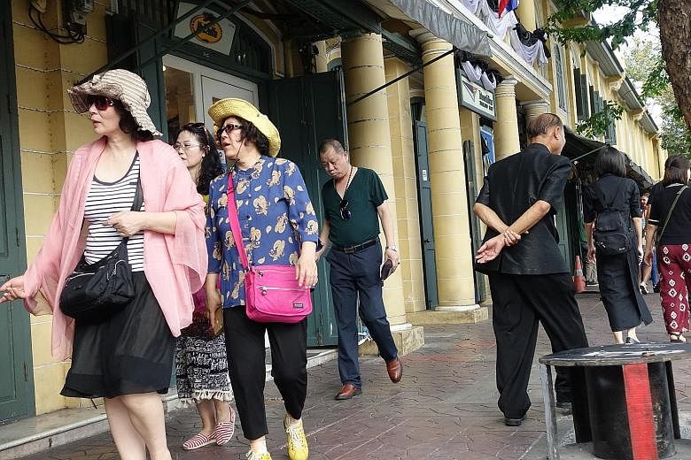 Left: The bright attire of Chinese tourists strikes a contrast against mourners on their way to Bangkok's Grand Palace to pay respects to the late king. Top: Singapore hotel chain Clover opened an outlet in Bangkok in March last year. Its occupancy r