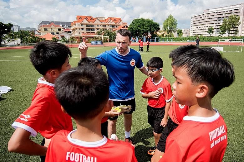 Volunteer assistant coach Kenneth McGeough briefing the participants of the ActiveSG football academy. SportSG will get more involved in football by holding the purse strings for the Football Association of Singapore.