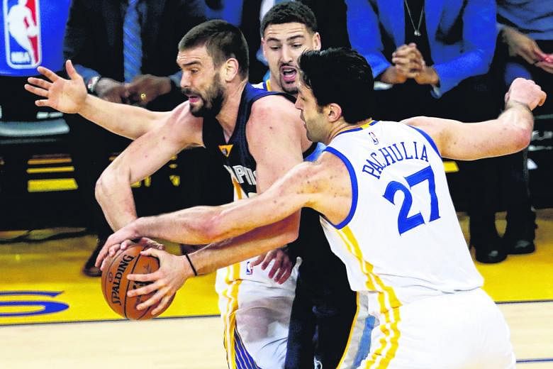 Memphis' Marc Gasol holding on to the ball against Golden State's Zaza Pachulia and Klay Thompson during the first half. The Grizzlies beat the Warriors 128-119.