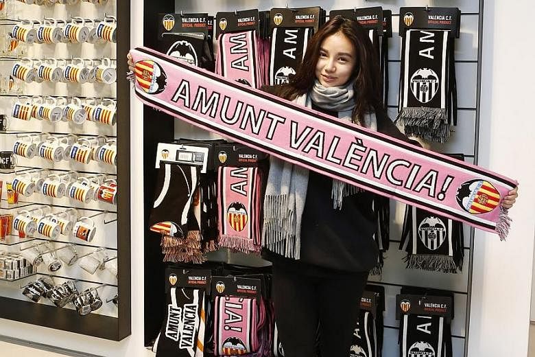 Kim, the 24-year-old daughter of Valencia owner Peter Lim, holding a scarf with a phrase that translates to "Go Valencia".