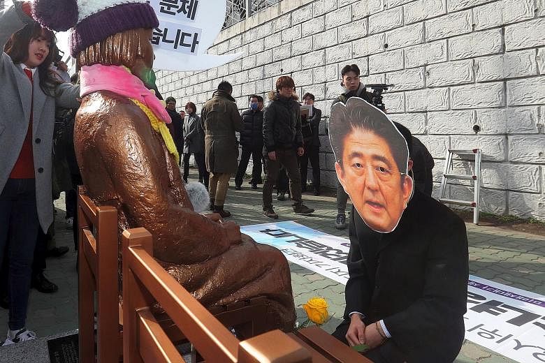 A South Korean protester donning a mask of Japanese Prime Minister Shinzo Abe, in a mock apology in front of a "comfort woman" statue, outside the Japanese consulate in Busan last week.