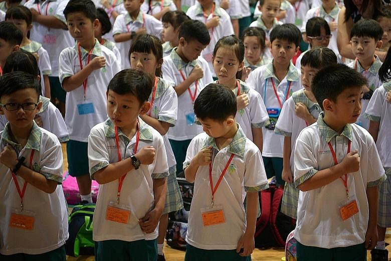 Westwood Primary 1 pupils figuring out how to place their fist on their chest before reciting Singapore’s National Pledge during morning assembly last Tuesday. 