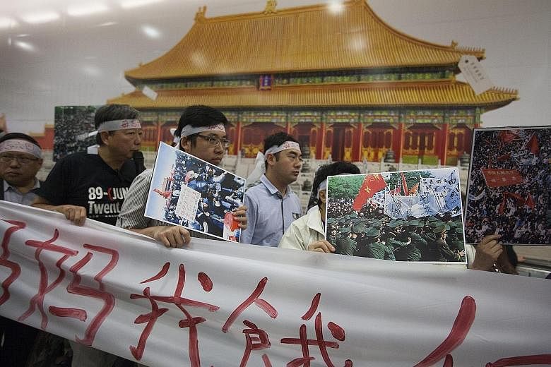 Pro-democracy protesters gathering in front of a banner advertising the Palace Museum project at the Central MTR station on Monday. Mrs Lam has come under fire for not seeking public feedback before signing the MOU on the development of the museum.