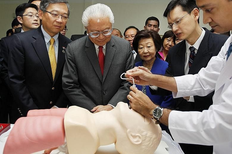 President Tony Tan Keng Yam (centre) and his wife Mary are given a demonstration of a medical technique during a hospital visit in Phnom Penh. At left is Singapore's Health Minister Gan Kim Yong.