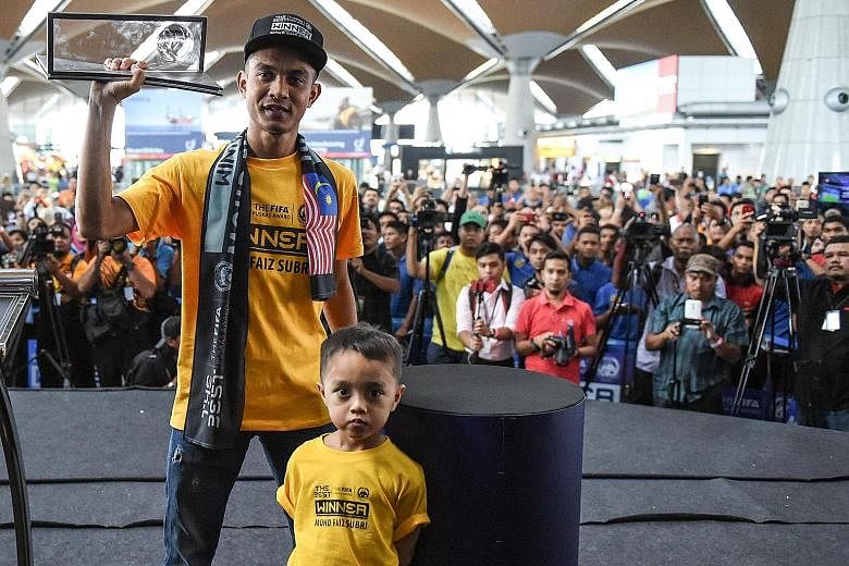 Malaysian footballer Mohd Faiz Subri poses with his award behind his son Akief Fayyadh at Kuala Lumpur International Airport.