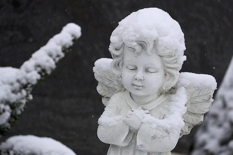 A statue blanketed in snow in the main cemetery of the German town of Hanau, near Frankfurt.