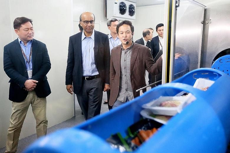 DPM Tharman, accompanied by Mr Kwan (left), being shown how a high-pressure processing line works. Mr Chan (right) said the machine could increase the shelf life of The Soup Spoon's soup sachets from two weeks to three months, which would allow the c