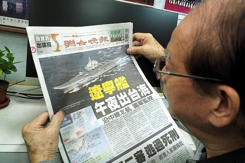 A man in Taiwan reading on Wednesday about China's aircraft carrier Liaoning passing through the Taiwan Strait. China's sole aircraft carrier left the waterway separating China from the island yesterday.