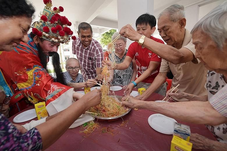 Singapore Press Holdings (SPH) staff, one dressed as the God of Fortune, "lo hei" (tossing yusheng) with seniors from the AWWA Senior Community Home. SPH brought early Chinese New Year cheer to 120 residents yesterday, with more than 20 staff volunte