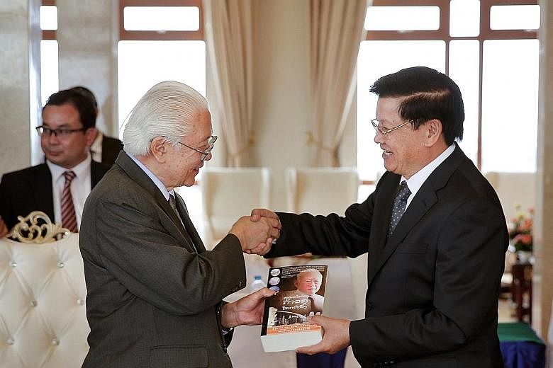 Dr Tan presenting a Lao edition of the book, From Third World To First: The Singapore Story From 1965 To 2000, which was written by founding prime minister Lee Kuan Yew, to Mr Thongloun.
