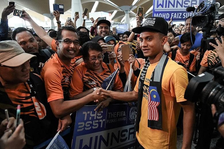 Malaysian footballer Mohd Faiz Subri (right) greeting supporters at the Kuala Lumpur International Airport after winning the Puskas Award The 29-year-old Penang forward has never started for his national team.