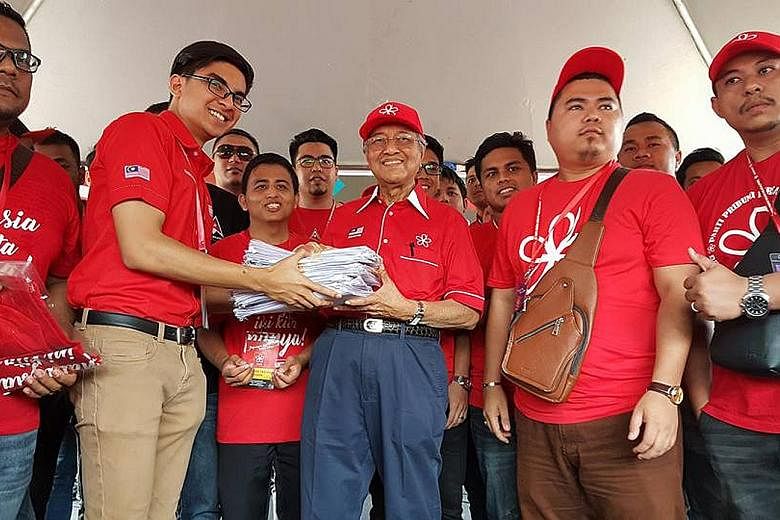 Dr Mahathir receiving application forms for membership in Parti Pribumi Bersatu Malaysia from the party's youth wing chief Syed Saddiq Syed Abdul Rahman at Shah Alam stadium yesterday.