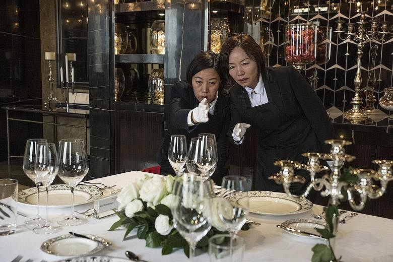 Ms Liu Janmin (left) and Ms Zhang Ling, who are studying to be butlers, checking the alignment of glasses on a table set for a formal dinner.