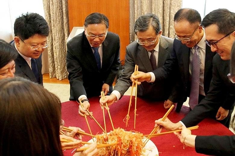 Diplomats from Singapore and China doing the traditional "prosperity toss" of yusheng at lunch yesterday, ahead of the Chinese New Year.