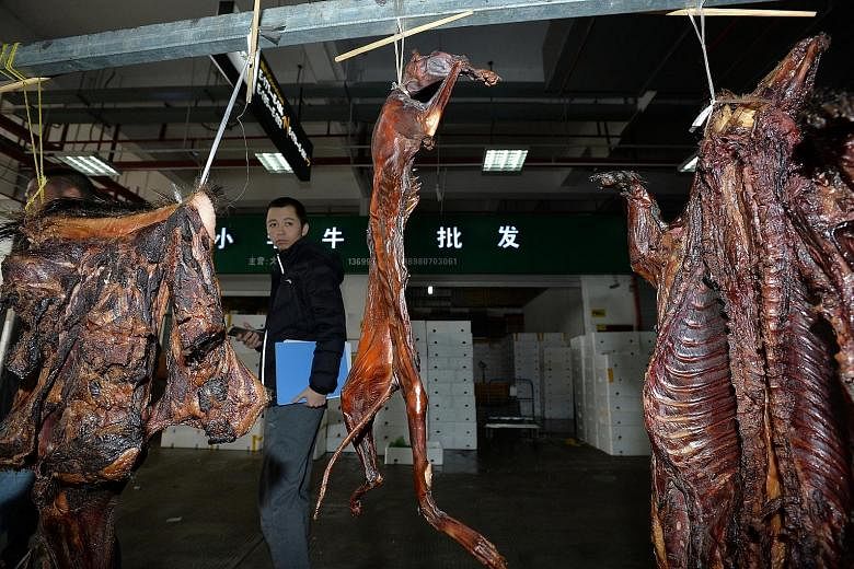 A law enforcer seen at a shop selling cat meat as fake wild game in Chengdu, Sichuang, on Nov 28 last year. In a new case, some 50 factories in Duliu were reportedly using unapproved ingredients unfit for human consumption, like industrial salt, in s