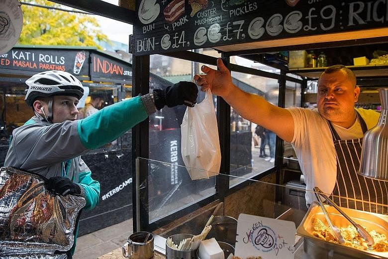 A Deliveroo employee picks up an order from an eatery in Camden Town in north London. Deliveroo's plan to hire more technology workers will expand its presence in London.