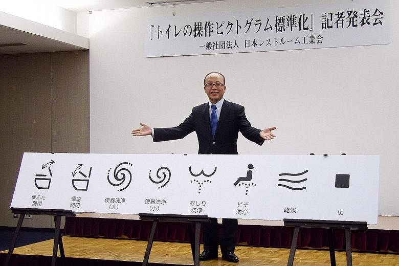 Mr Madoka Kitamura, chairman of the Japan Sanitary Equipment Industry Association, showing off the standardised icons for high-tech toilet functions in Tokyo.