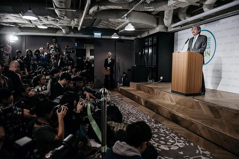 Mr Tsang (at the podium) announcing his bid for the city's top job at a news conference yesterday in Hong Kong. He was spotted holding a mobile phone with the mascot of the crisp brand Mr Pringles on it. The former Hong Kong finance chief, who has be