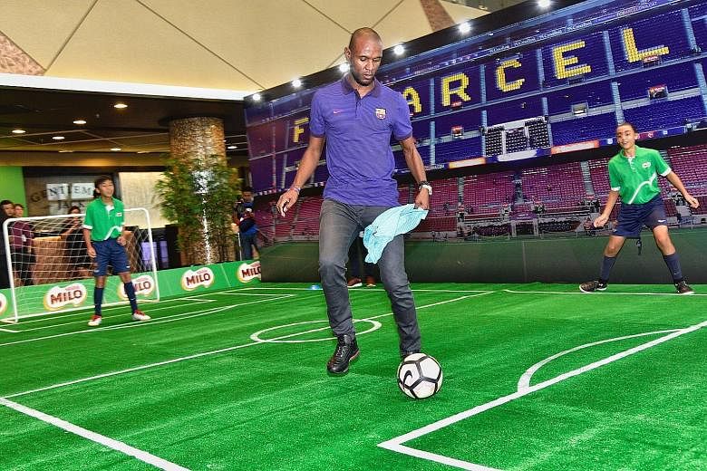 Four-time La Liga champion Eric Abidal playing football with children from FCBEscola Singapore - the Barcelona football school here - at a Milo event at the Sports Hub yesterday.