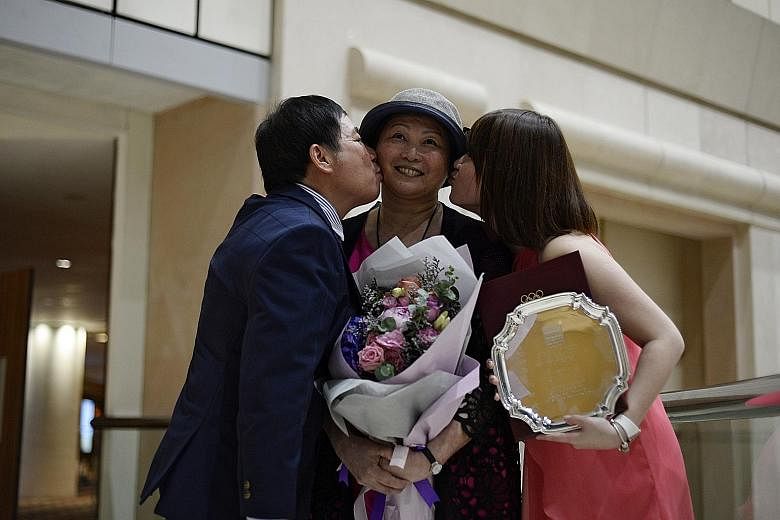 Gymnastics coach Zhu Xiaoping receiving kisses from her husband Lin Zhenqiu and daughter Pan Pan after getting a special award for fortitude at the Singapore Sports Awards last year.