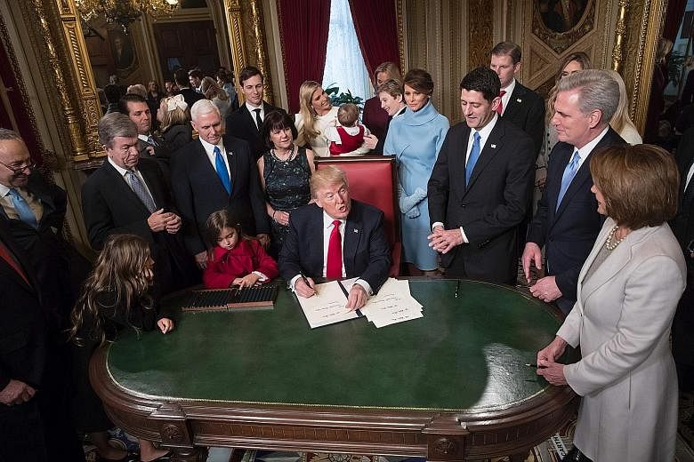 Mr Trump signing two of his Cabinet nominations into law in the presence of the leaders of his administration and Congress as well as his family in the President's Room of the Senate in Washington, DC last Friday. Behind him, his son Barron can be se