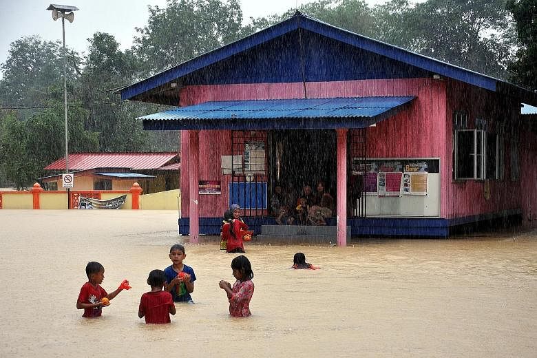 Children, undaunted by floodwater, playing in front of the Kampung Tasik flood relief centre in Setiu, Terengganu, on Saturday. MetMalaysia issued a heavy rain warning for the state and Pahang yesterday, and said it expected moderate rain to continue
