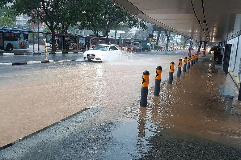 Cleaners clearing a flooded walkway at the National University of Singapore's University Town yesterday morning. Flash floods occurred in several places yesterday, including the area near Haw Par Villa MRT station. Experts say the rain is typical for