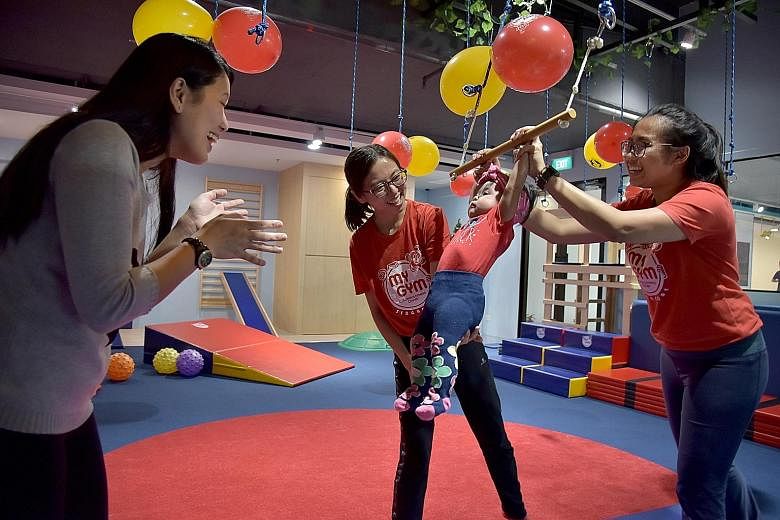 Madam Joanne Oglimen (left) watching her seven-month-old daughter Nathalia Yambao playing on a swing, supervised by gym coaches at the Bove megastore in Suntec City yesterday. Besides selling maternity wear and baby products, the store has play areas