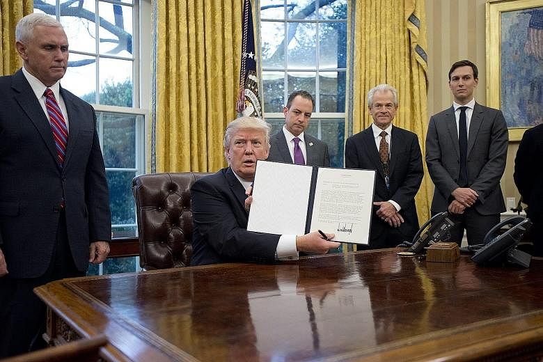 US President Donald Trump with an executive order withdrawing the country from the Trans-Pacific Partnership in the Oval Office of the White House in Washington on Monday. He declared that he had "terminated" it in line with election pledges to scrap